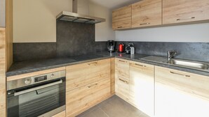 A modern kitchen with wooden cabinets, a stainless steel sink, and a built-in oven. - Renovated 2BR apartment at ski slopes with parking - Courchevel 1850 (Courchevel 1850)