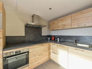 Eine moderne Küche mit Holzschränken, einer Edelstahlspüle und einem eingebauten Backofen.