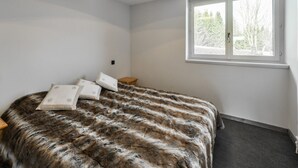 A bedroom with a large bed, a window with a view of trees, and a ceiling light fixture. - Renovated 2BR apartment at ski slopes with parking - Courchevel 1850 (Courchevel 1850)