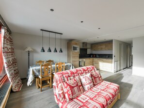 Ein modernes Wohnzimmer mit einer Couch, einem Esstisch, Stühlen und einer Küchenzeile mit Holdekor und Geräten.