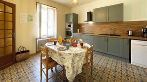 A compact kitchen with a dining table, chairs, a microwave, oven, and a sink.