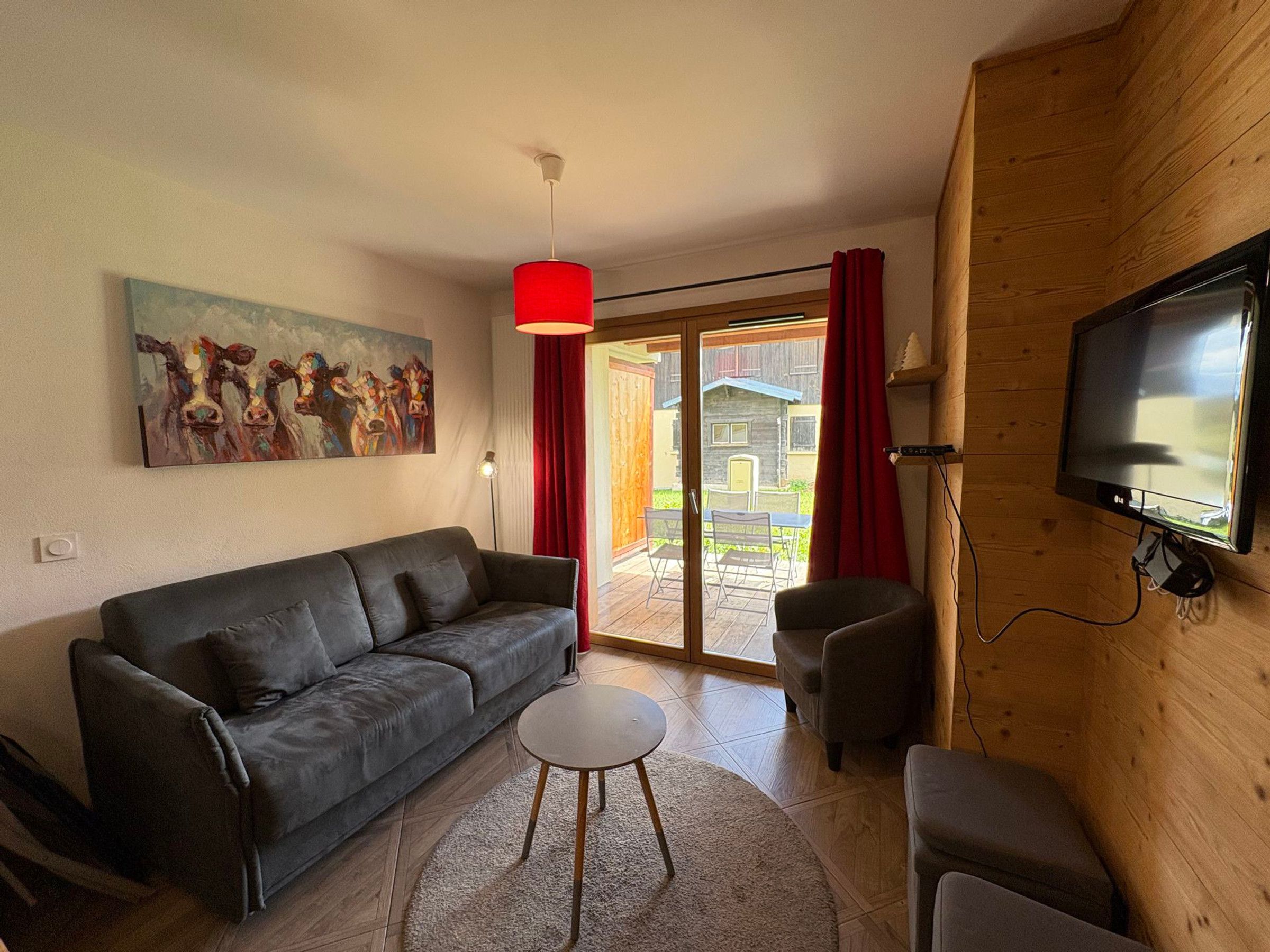 A living room with a sofa, a small table, a TV, and a painting on the wall.