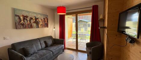 Un salon avec un canapé, une petite table, un téléviseur et un tableau accroché au mur.