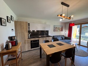 A modern kitchen with a dining area, a sofa, and a painting on the wall.