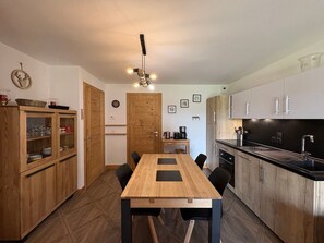 A modern kitchen with wooden cabinets, a dining table with chairs, and a built-in oven. - 3-room apartment, 2 bathrooms, near slopes, pets allowed (Hauteluce)