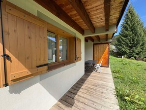 A wooden exterior with large windows and a covered patio area.
