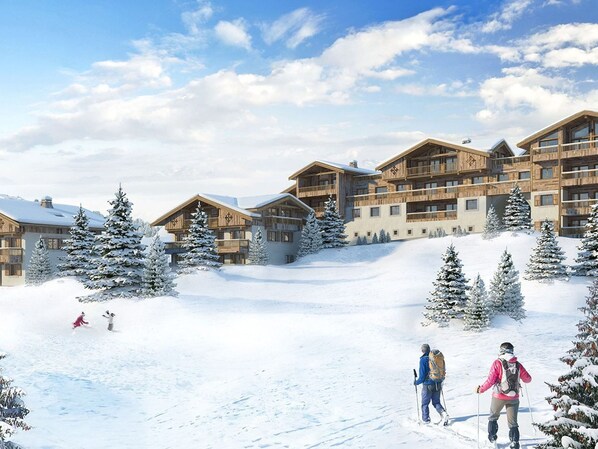 A ski resort with multiple wooden buildings, snow-covered trees, and skiers on the slopes.