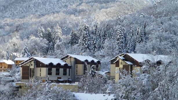 A cluster of chalet-style buildings surrounded by snow-covered trees. - Cozy studio with west balcony, WIFI, covered parking (Brides-les-Bains)