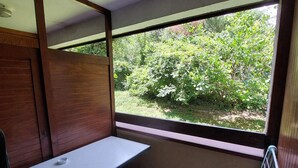 A small room with a single table and a window providing a view of greenery outside. - Cozy studio with west balcony, WIFI, covered parking (Brides-les-Bains)