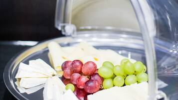 A cheese platter with grapes and a clear dome cover.
