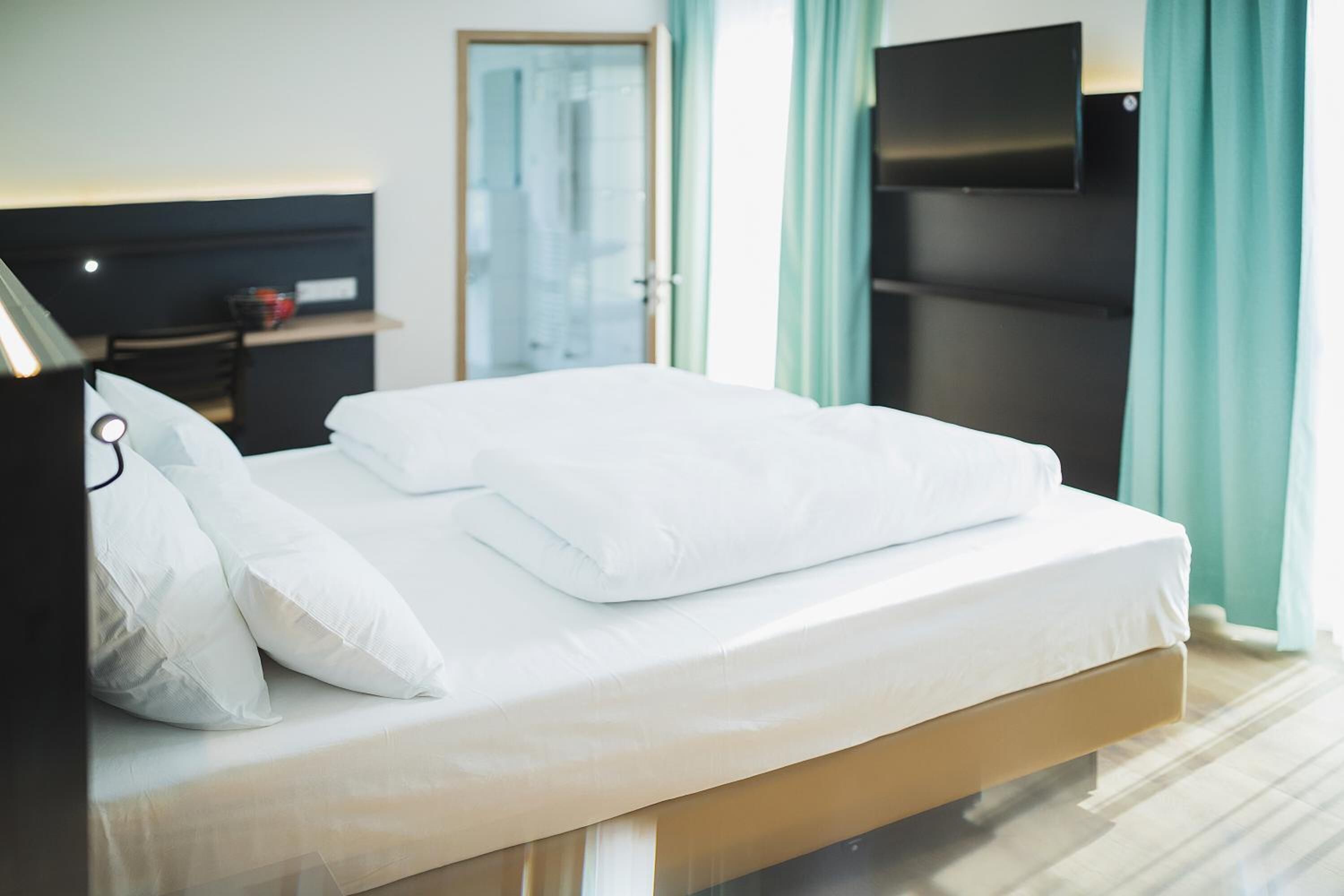 Un lit bien fait, avec du linge de lit blanc, dans une chambre d'hôtel.