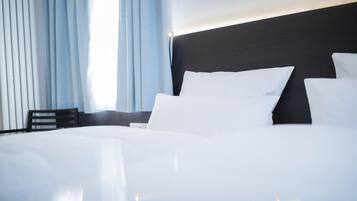 A neatly made bed with white linens in a hotel room.