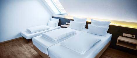 A modern hotel room with two single beds, a skylight, a bedside table, and a nightstand.