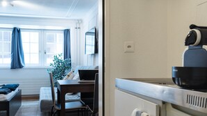 En kompakt bolig med spiseplads, tekøkken og et vindue med gardiner.