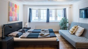 Et moderne soveværelse med seng, sengeborde, en sofa og et vindue med gardiner.