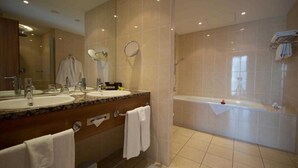 Une salle de bain moderne avec deux lavabos, un grand miroir, une baignoire et un espace douche.