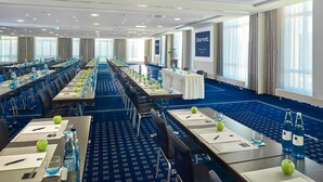 Une salle de conférence avec de longues tables, des chaises et des bouteilles d’eau.