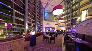 Un vaste espace intérieur aménagé avec de nombreux coins salon, un bar et un grand plafond éclairé.