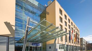 Ein Dorint Hotel mit moderner Glasfassade, einem überdachten Eingang und einem Parkplatzschild.