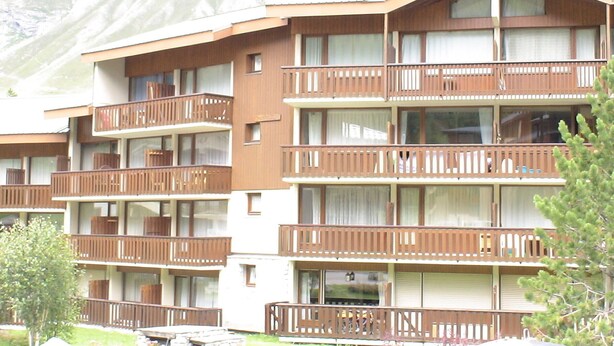 A multi-story hotel with balconies, a stone facade, and a mountainous backdrop. - Cozy studio for 4, near Val d'Isère center, with WIFI (Val-d'Isère)