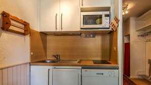A compact kitchen with white cabinets, a microwave, a sink, and a dishwasher. - Cozy studio for 4, near Val d'Isère center, with WIFI (Val-d'Isère)