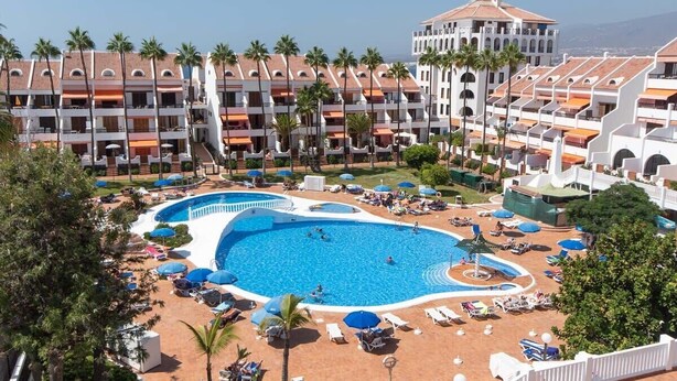 Ein Resort mit mehreren Swimmingpools, Palmen und Blick auf den Ozean.
