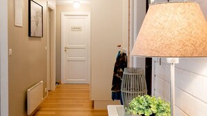 A hallway with a wooden floor, a white door with a sign, a lamp, and a framed picture on the wall. - Odinsve Country Home (Selfoss)