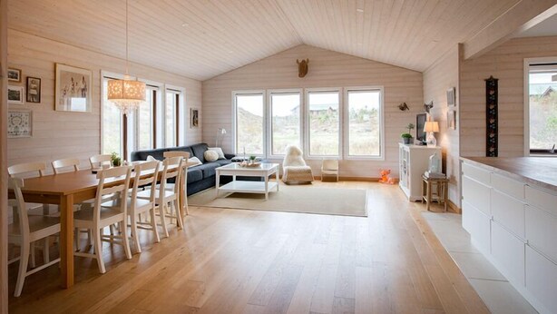 A spacious living area with a wooden ceiling, a dining set, a sofa, and large windows offering a view of the outdoors. - Odinsve Country Home (Selfoss)