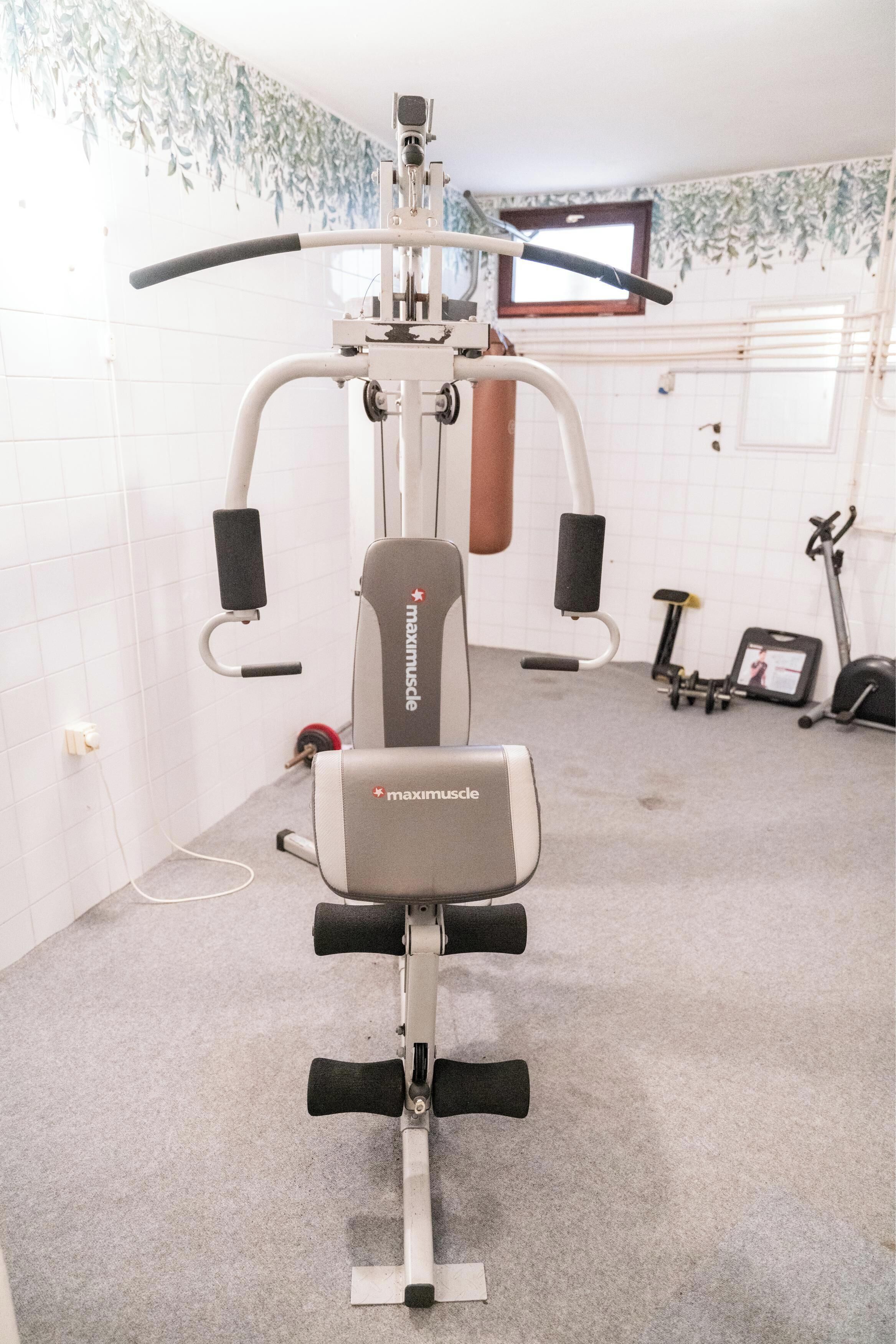 Un gimnàs amb una màquina d'exercici multifuncional anomenada 'maximuscle'.