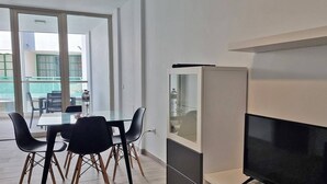 A modern living room with a glass dining table, black chairs, a flat-screen TV, and a cabinet. - Costa Azul - 3 Left (Puerto de Naos)