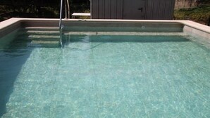 A rectangular swimming pool with clear water, surrounded by a concrete deck.