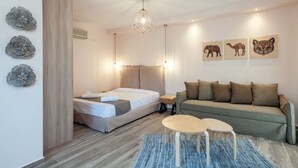 A modern hotel room with a bed, a sofa, a small table, and decorative wall art. - Iliovasilema (Lemnos)