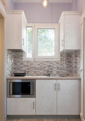 A kitchen with white cabinets, a tiled backsplash, a window above the sink, and a built-in microwave.