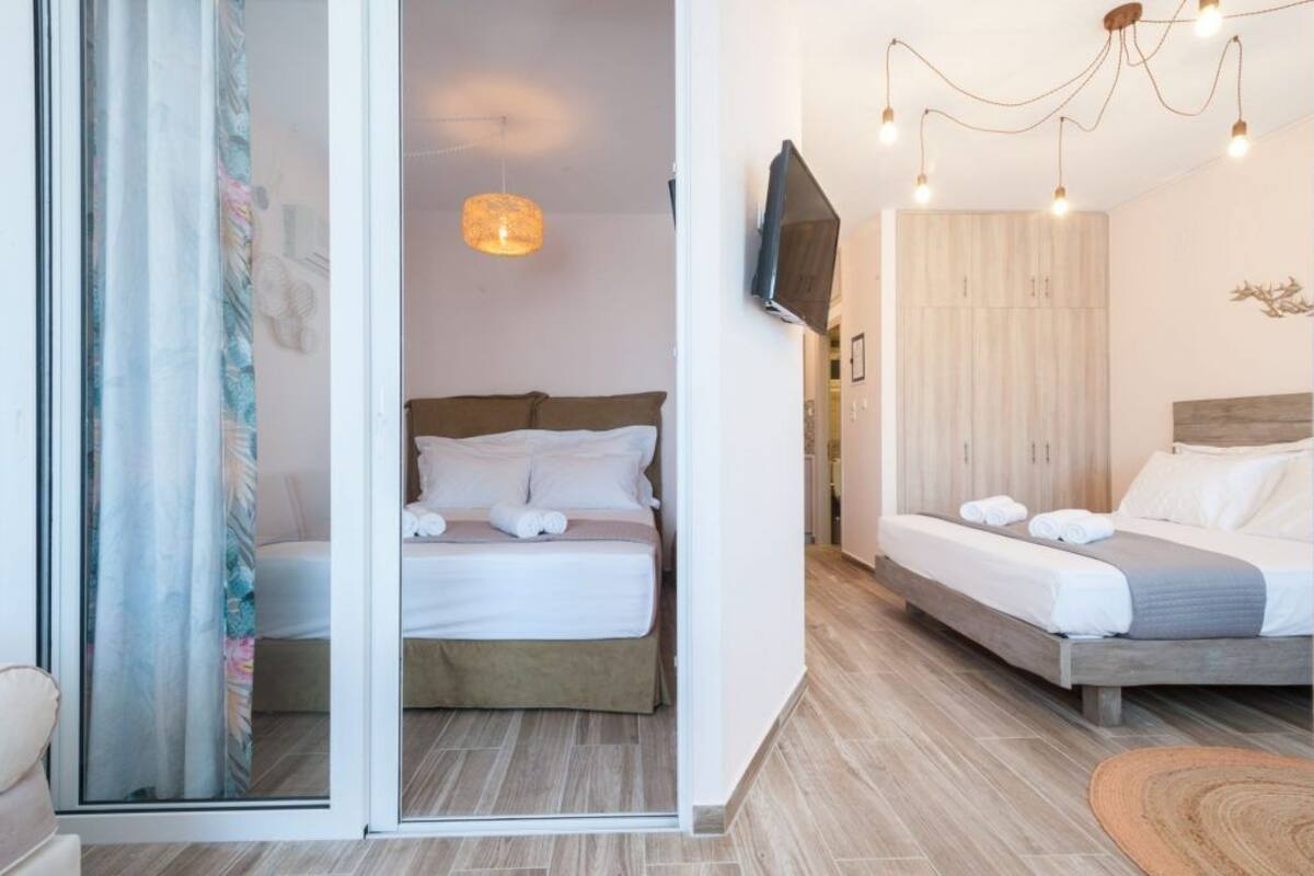 A bedroom with two beds, a TV, and a chandelier.
