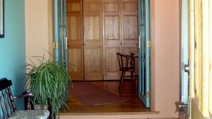 Une porte en bois surmontée d’une guirlande de fleurs, qui donne sur une pièce dotée d’un plafond en bois et d’un luminaire.
