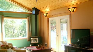 Un salon chaleureux avec un plafond en bois, une radio ancienne, un téléviseur et un canapé recouvert d’un tissu à motifs floraux.