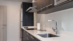 A modern kitchen with dark wood cabinets, a white countertop, a stainless steel sink, and a built-in range hood. - Costa Azul 3 right (Puerto de Naos)