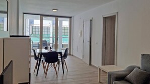 A modern apartment with a dining area, a sofa, and a view through large windows. - Costa Azul 3 right (Puerto de Naos)
