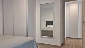 A bedroom with a bed, a large mirror, and a door leading to another room. - Costa Azul 3 right (Puerto de Naos)