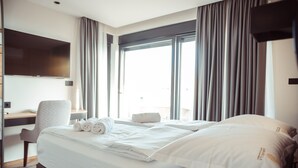 Een hotelkamer met een groot bed, een bureau, een stoel en een televisie die aan de muur is bevestigd.