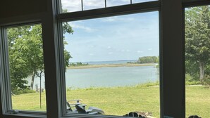 A room with large windows overlooking a lake, a grassy area, and trees. - Water Views from most rooms-on the Rappahannock River (Locust Hill)