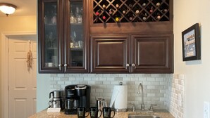 A kitchen with dark wooden cabinets, a wine rack, a coffee maker, and a sink. - Water Views from most rooms-on the Rappahannock River (Locust Hill)