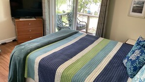 A bedroom with a bed, a TV, a dresser, and a balcony with a chair. - Water Views from most rooms-on the Rappahannock River (Locust Hill)