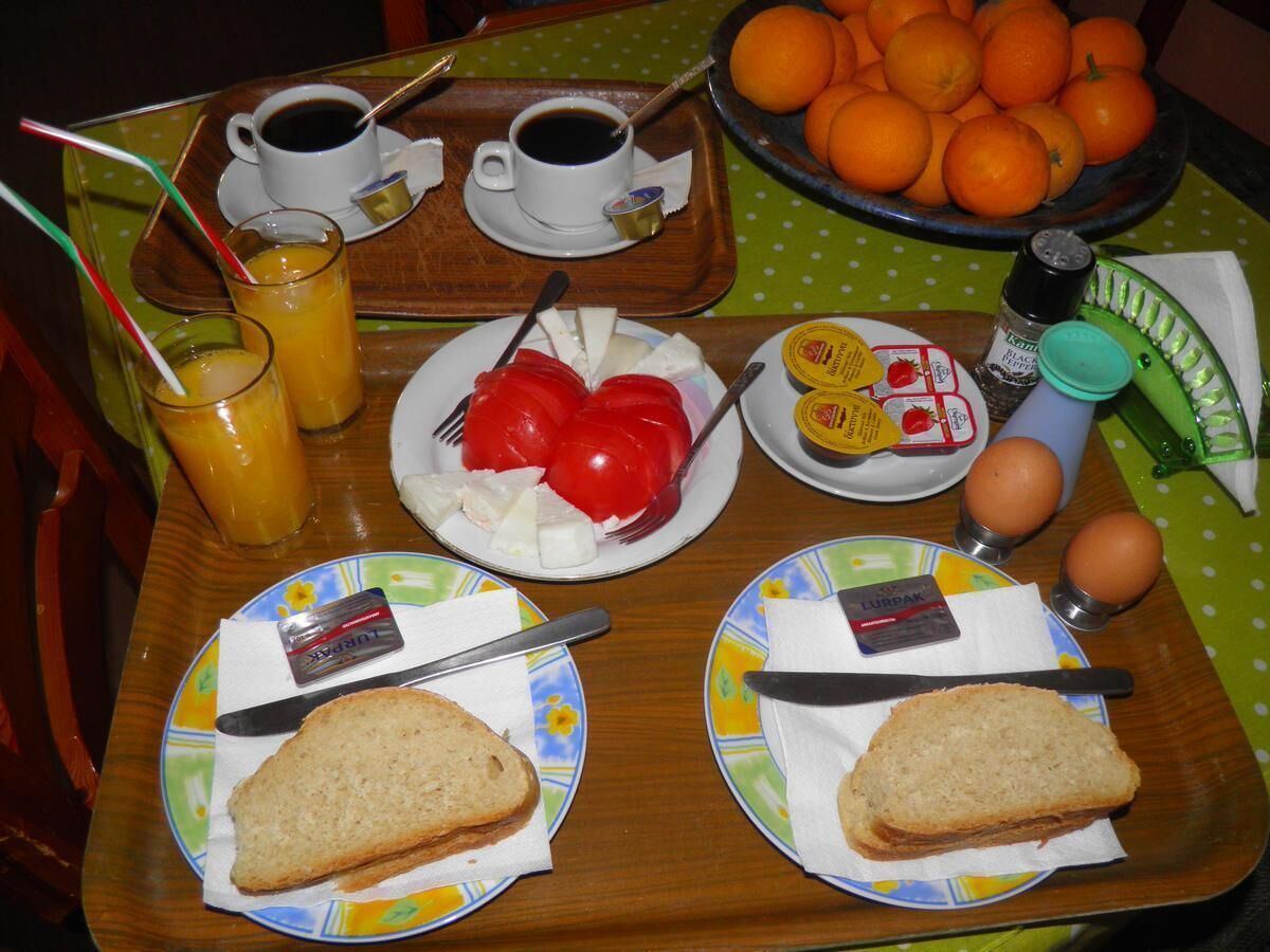 Uma bandeja de café da manhã com pão, queijo, tomates, ovos e laranjas.