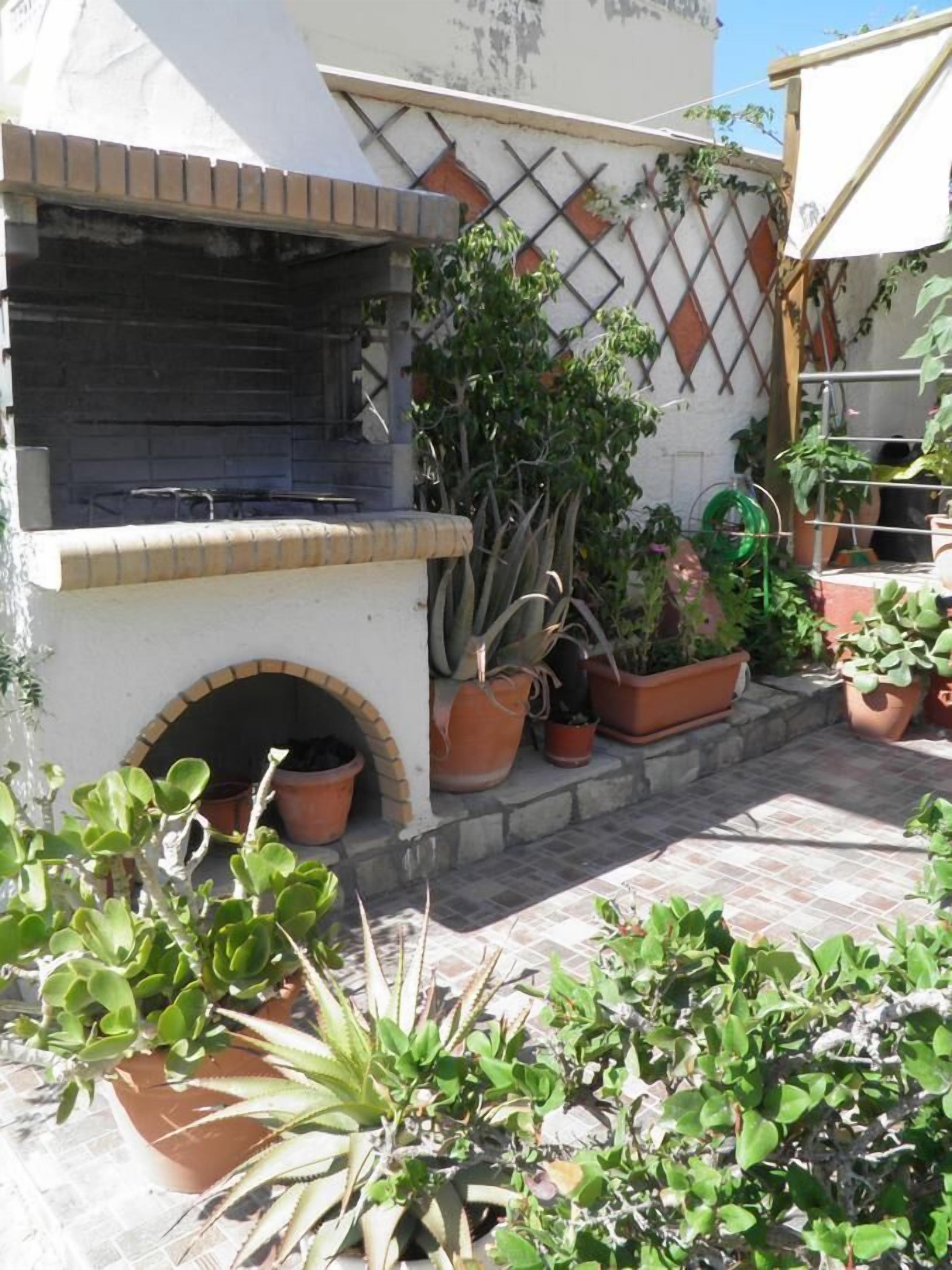 A patio with a brick oven, potted plants, and a lattice wall.