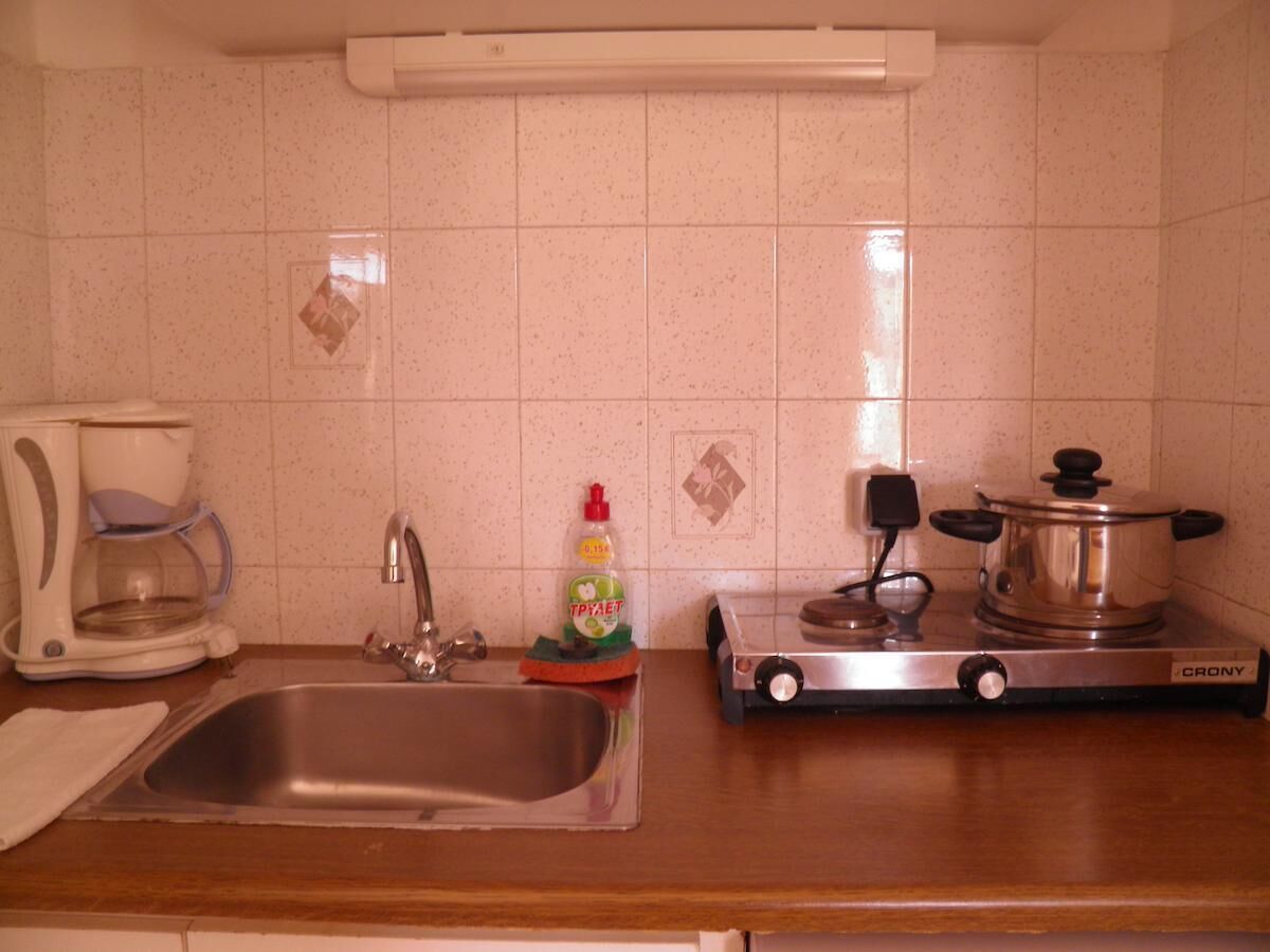 Une cuisine équipée d’un évier, d’une machine à café, d’un flacon de liquide vaisselle et d’une cuisinière.