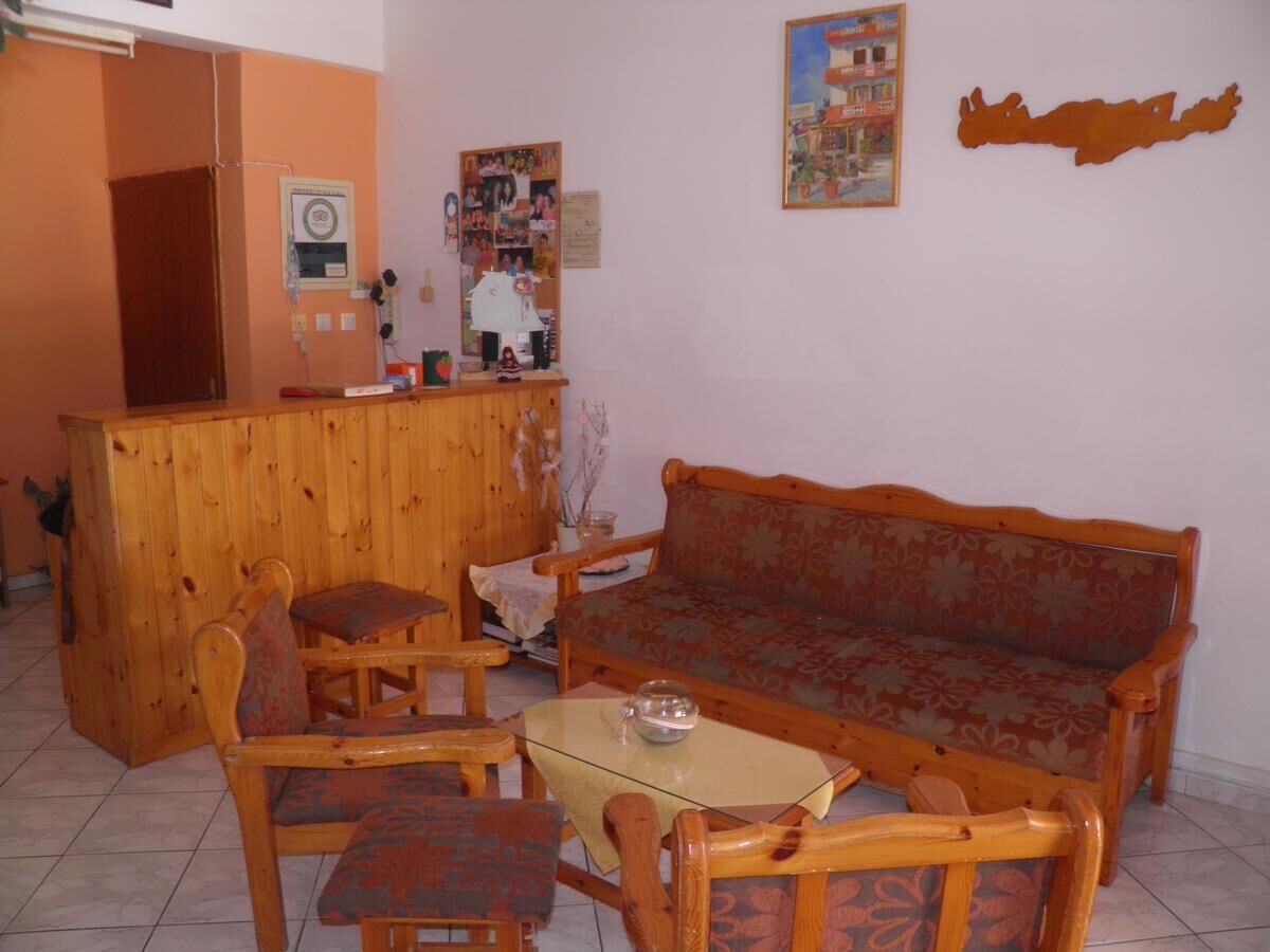 A cozy living room with a wooden sofa, two armchairs, a small coffee table, and a wooden cabinet.