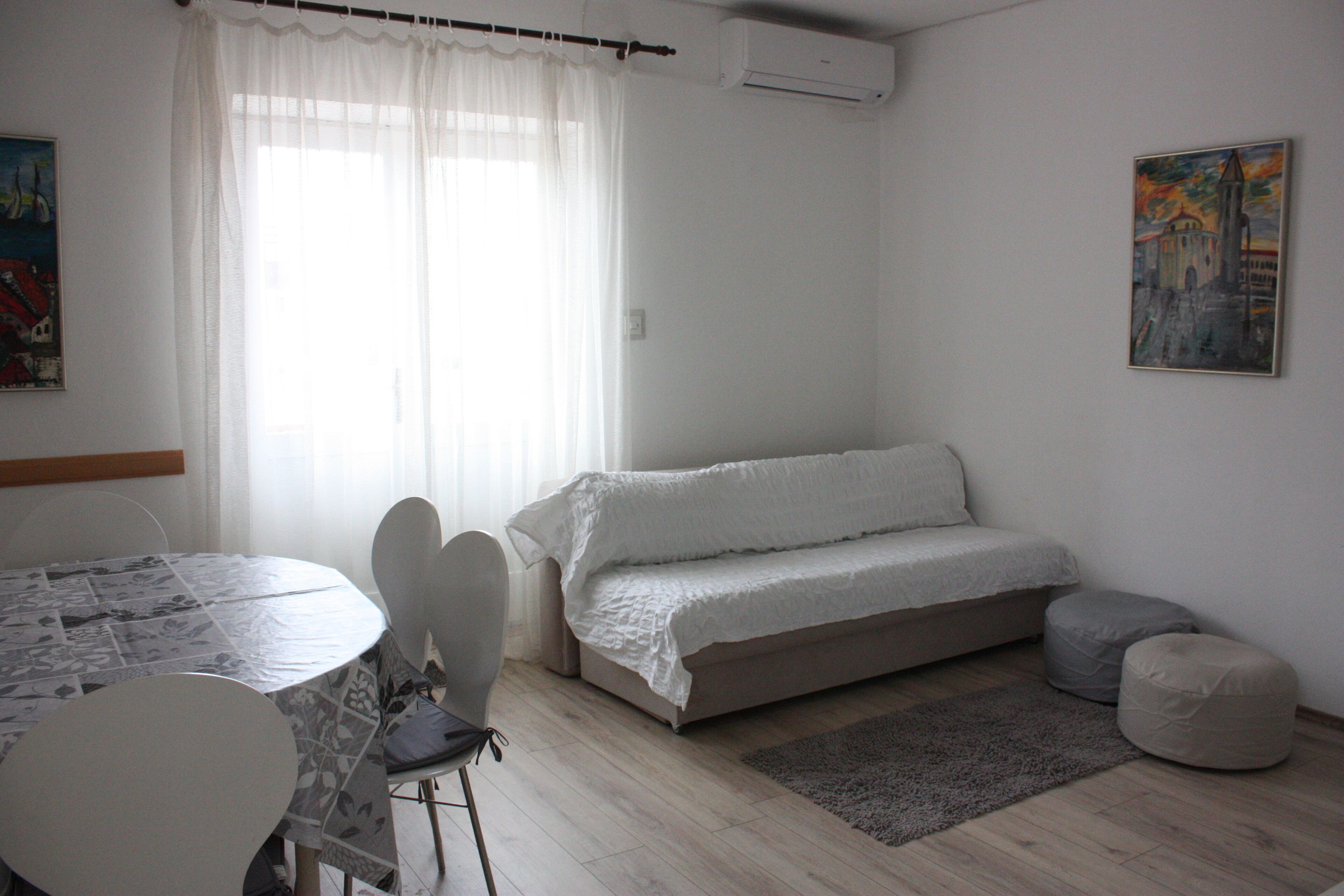 Una habitación con una cama, una mesa con sillas, una alfombra y un cuadro en la pared.