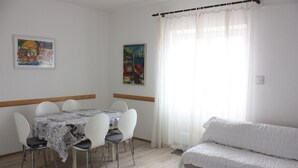 Un comedor con una mesa y sillas, un sofá y dos cuadros en la pared.