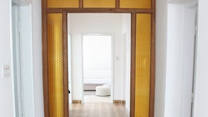 Un pasillo con baldosas de diseño, un marco de puerta de madera y vista a una habitación con una cama.